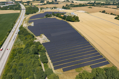 Luftaufnahme eines Solarparks mit Umspannwerk und Getreidesilos im Hintergrund