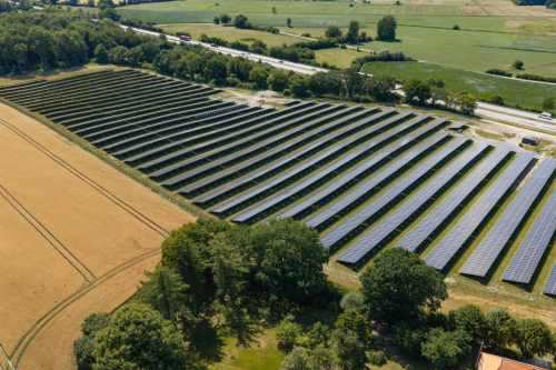 Luftaufnahme aufgeständerter bifazialer Solarmodule mit Grünfläche darunter