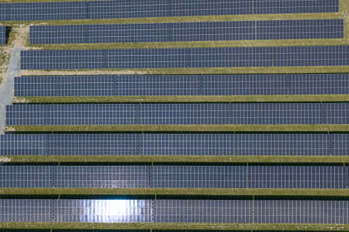 Senkrechte Luftaufnahme von oben auf die parallelen Modulreihen eines Solarparks
